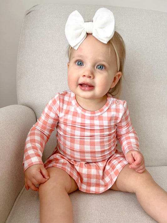 Baby skirted bodysuit dress in peach gingham. Made of bamboo for ultimate softness.
