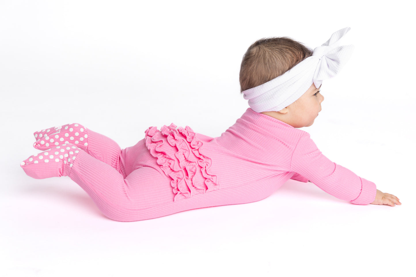 Baby in pink bamboo pajamas, also known as convertible zip romper.