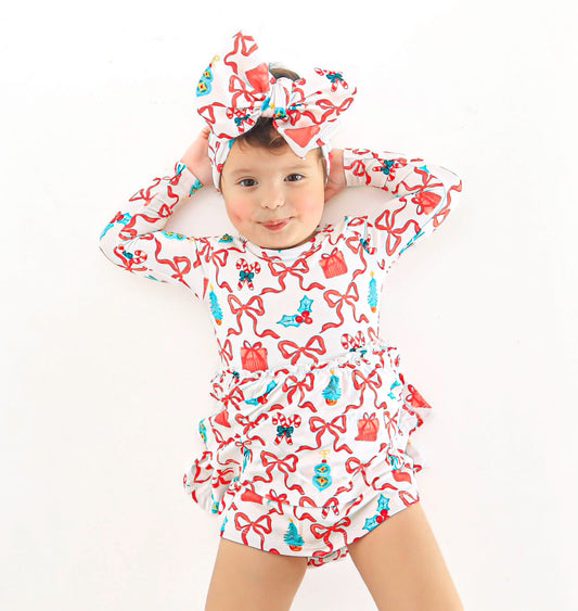 Adorable baby in a bamboo skirted bodysuit dress featuring a festive Christmas print of bows and candy canes, complete with a matching headwrap bow.