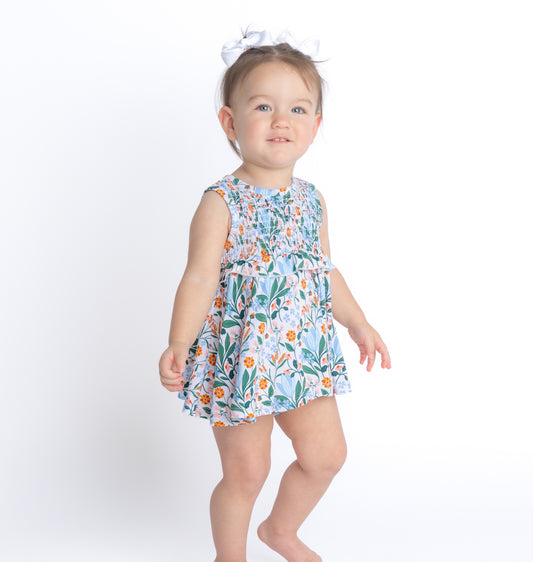 Shop our bamboo spring baby dress in a smocked onesie design with a blue and pink floral print. Eco-friendly and breathable for all-day comfort.