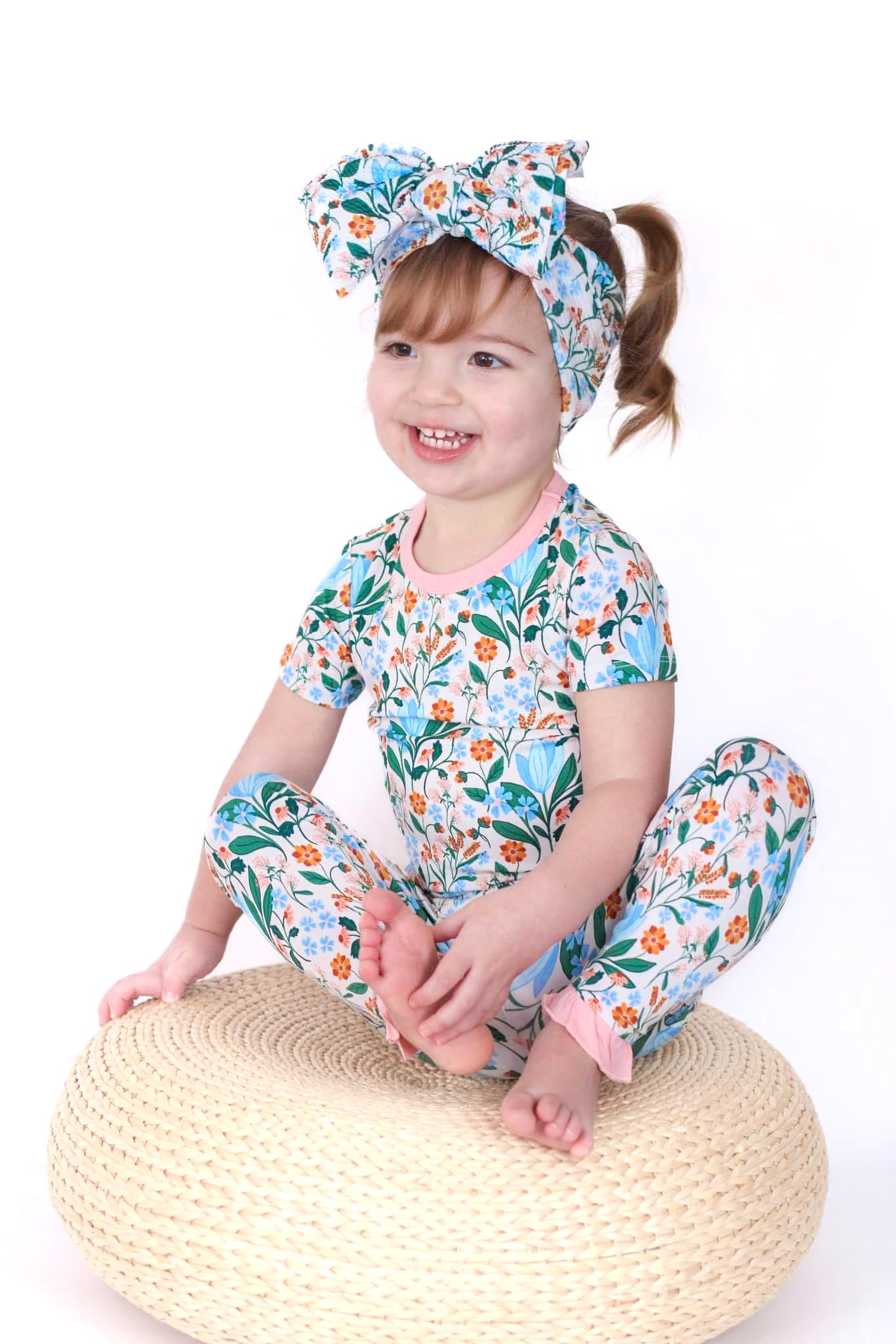 Shop our bamboo two-piece pajama set for toddlers and kids in a spring floral print with soft blue and pink flowers. Features ruffle details and eco-friendly, breathable fabric for all-night comfort.