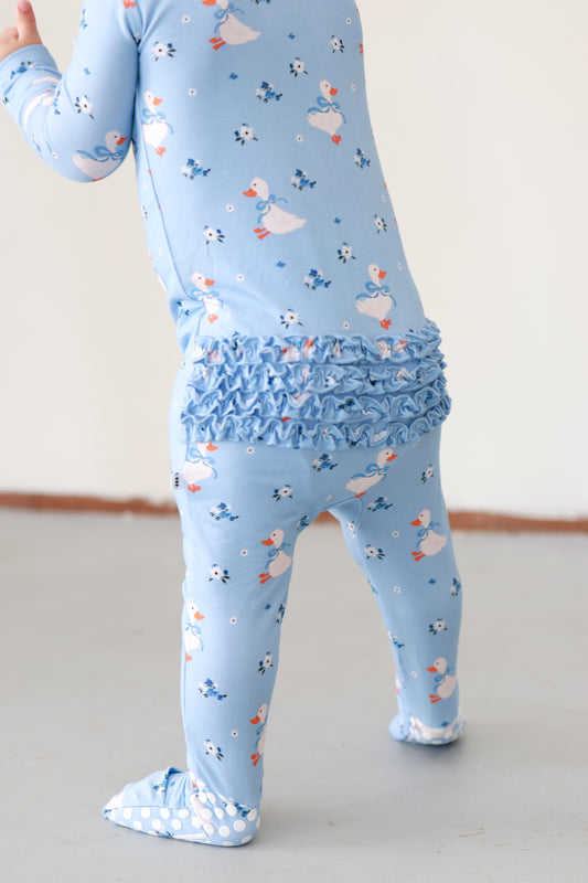 Light blue children's outfit with ruffled waistband and duck pattern on a plain background