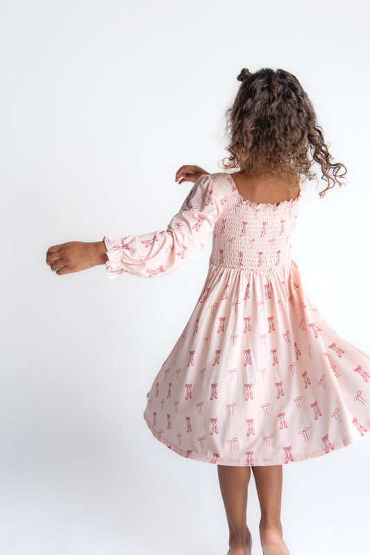 Girl twirling in a dress with ballet shoes and dainty bow print