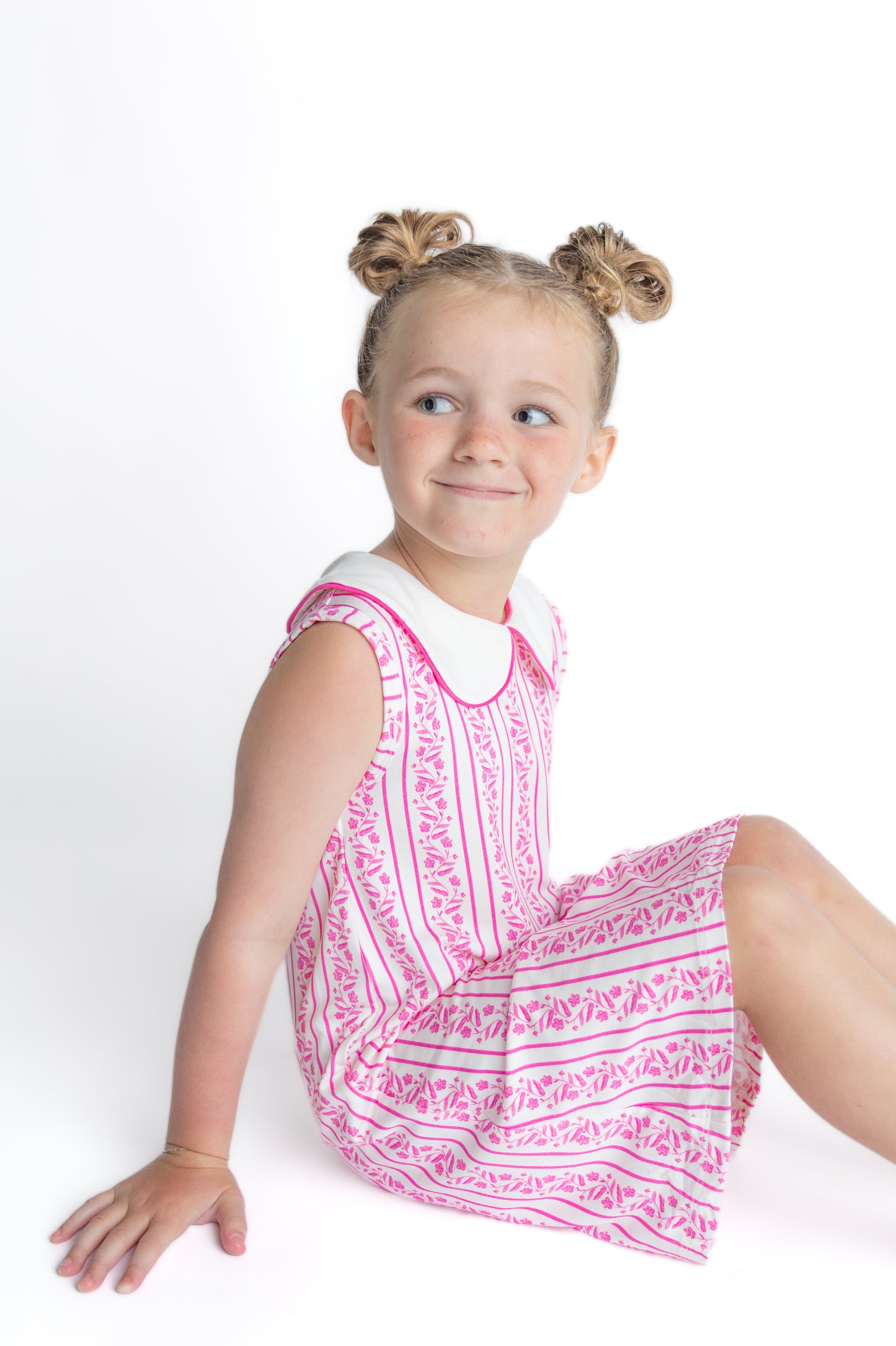 Young girl wearing a pink floral patterned dress on a white background