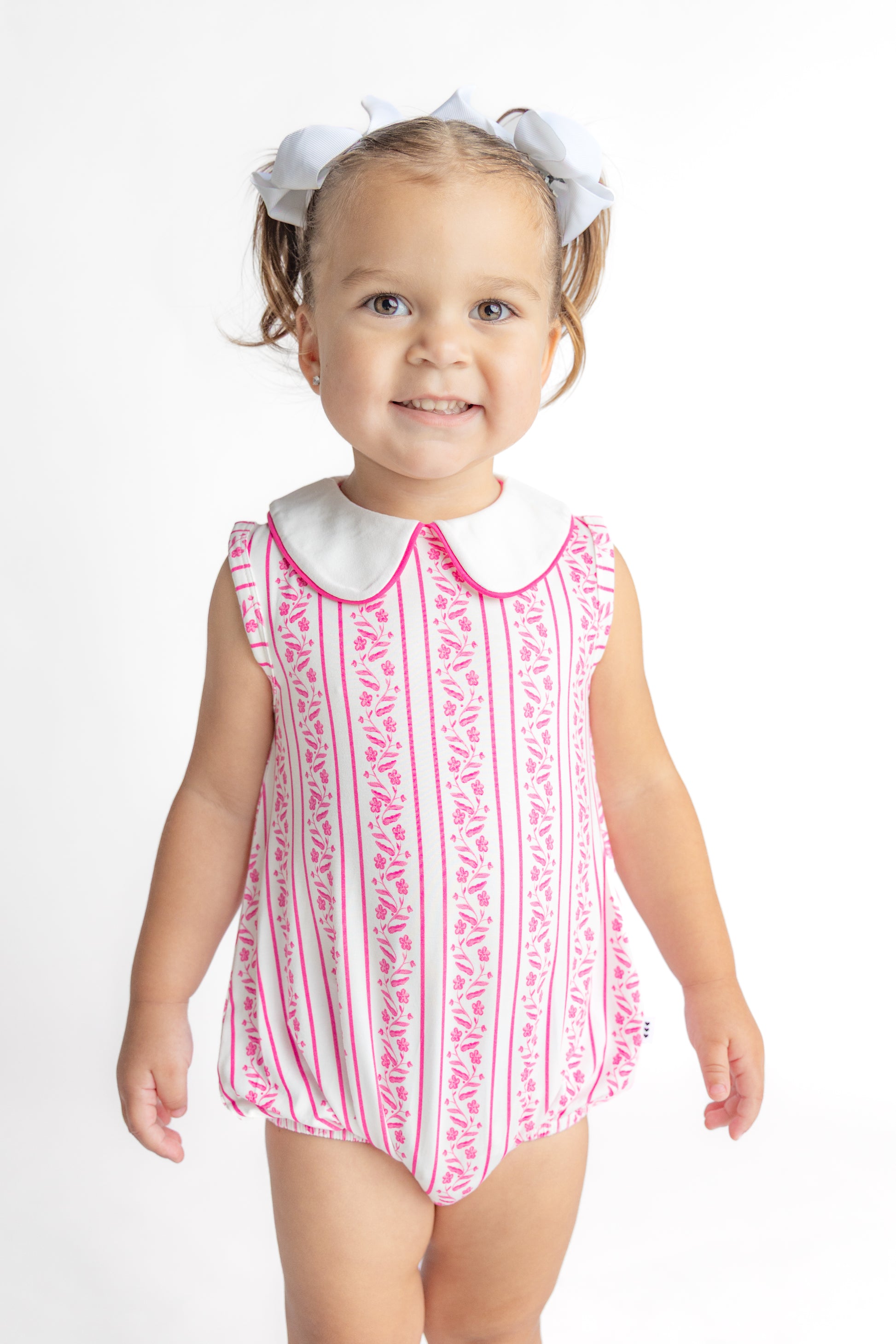 Baby girl wearing a pink floral bubble romper made from soft, breathable viscose from bamboo