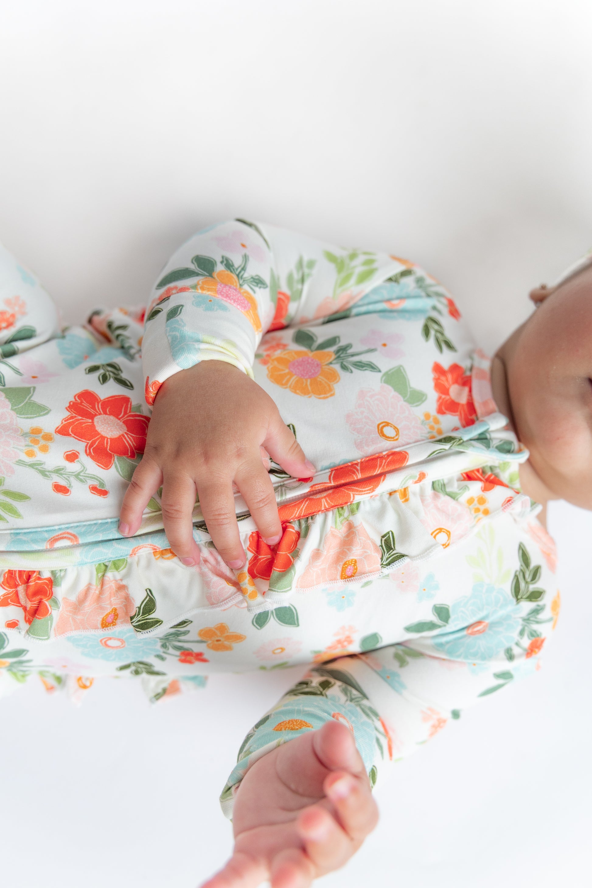 Baby in floral outfit with colorful flowers on a white background