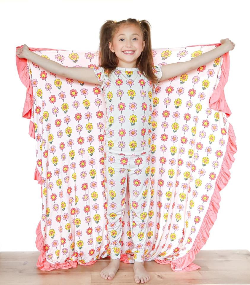 Cozy bamboo blanket featuring a cheerful smiling daisy print, ideal for swaddling and nursery decor.