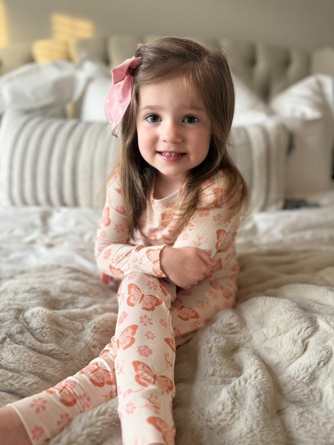 Toddler wearing Ella, a bamboo pajama set with a dainty butterfly and floral print. 