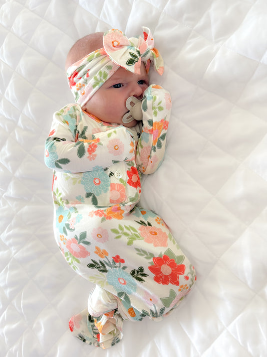 Baby girl wearing a floral bamboo knotted gown with a matching bow. 