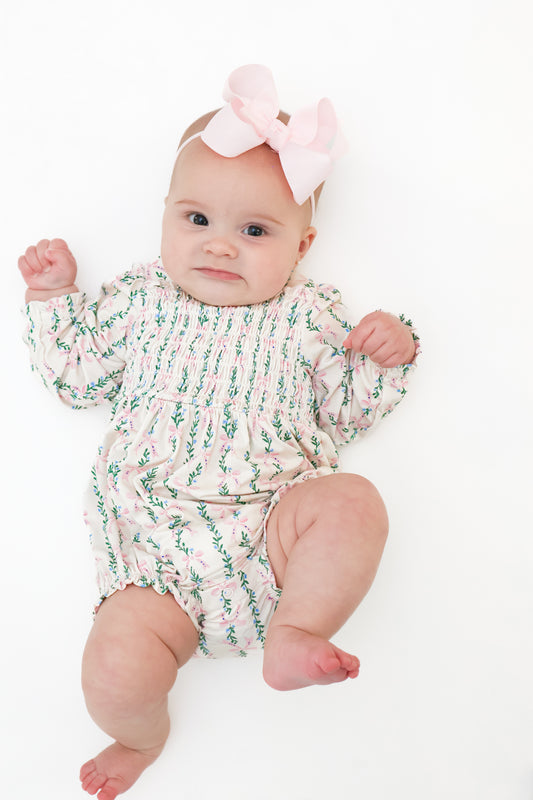 baby in floral and bow print smocked bubble romper made of bamboo fabric. 