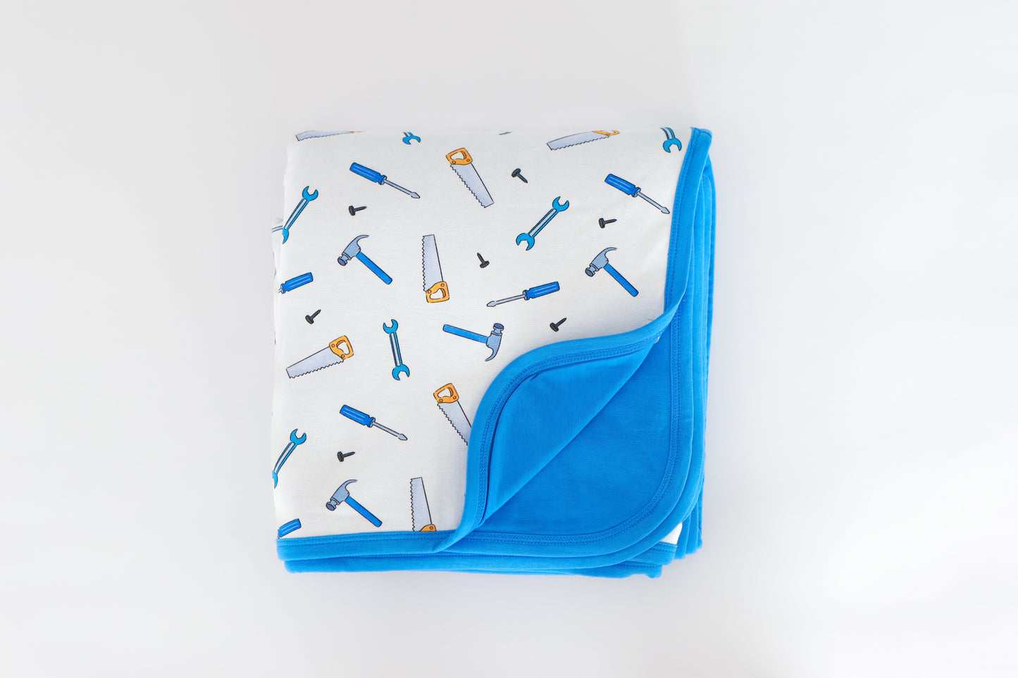Folded blue bamboo baby blanket with tool pattern on a white background