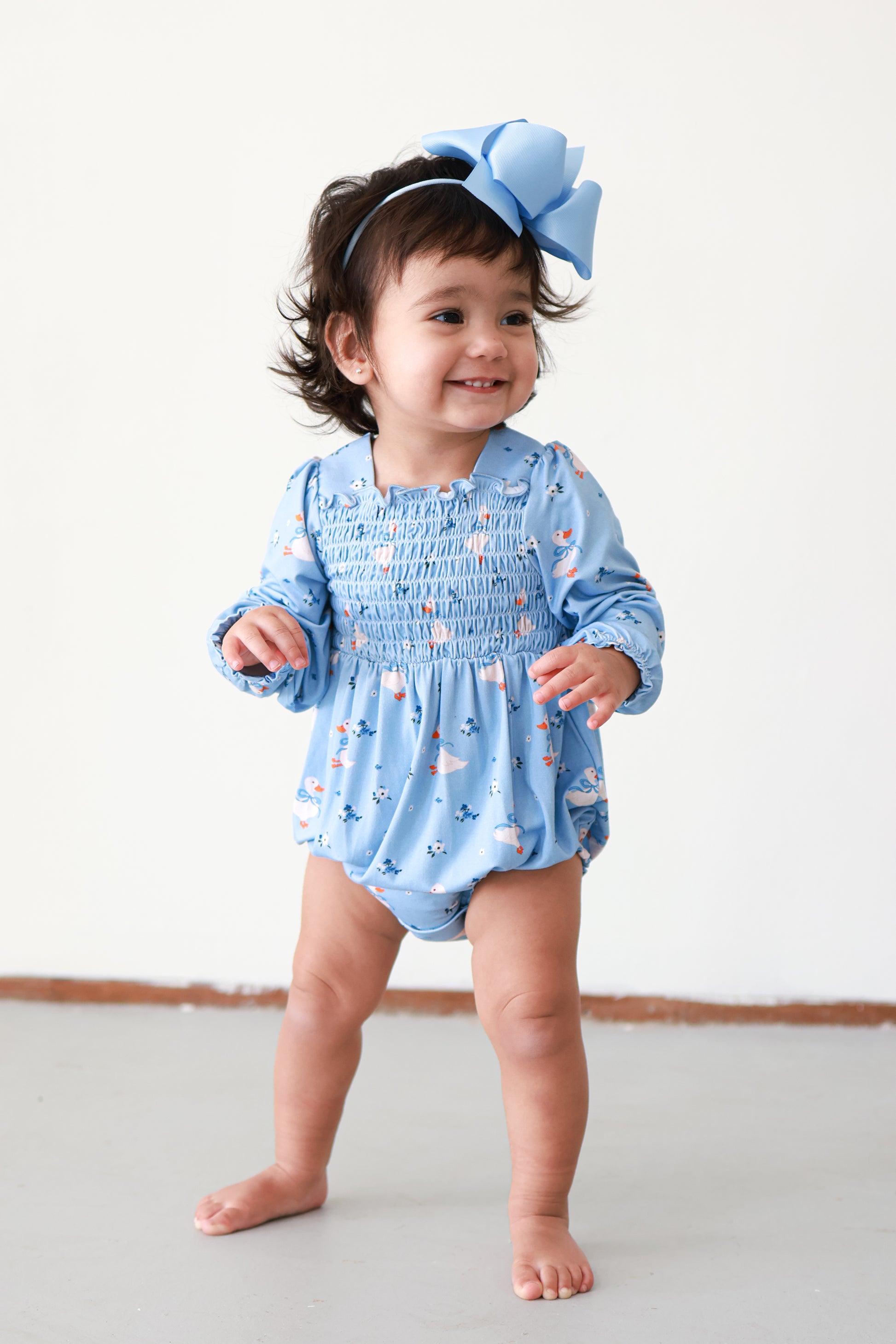 baby girl wearing blue duck print smocked bubble romper. 