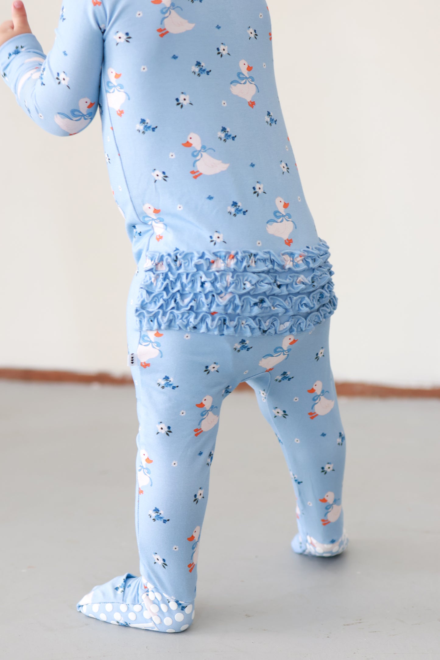 Light blue children's outfit with ruffled waistband and duck pattern on a plain background