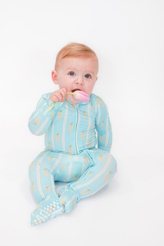 Baby in blue romper with carrot Easter print.