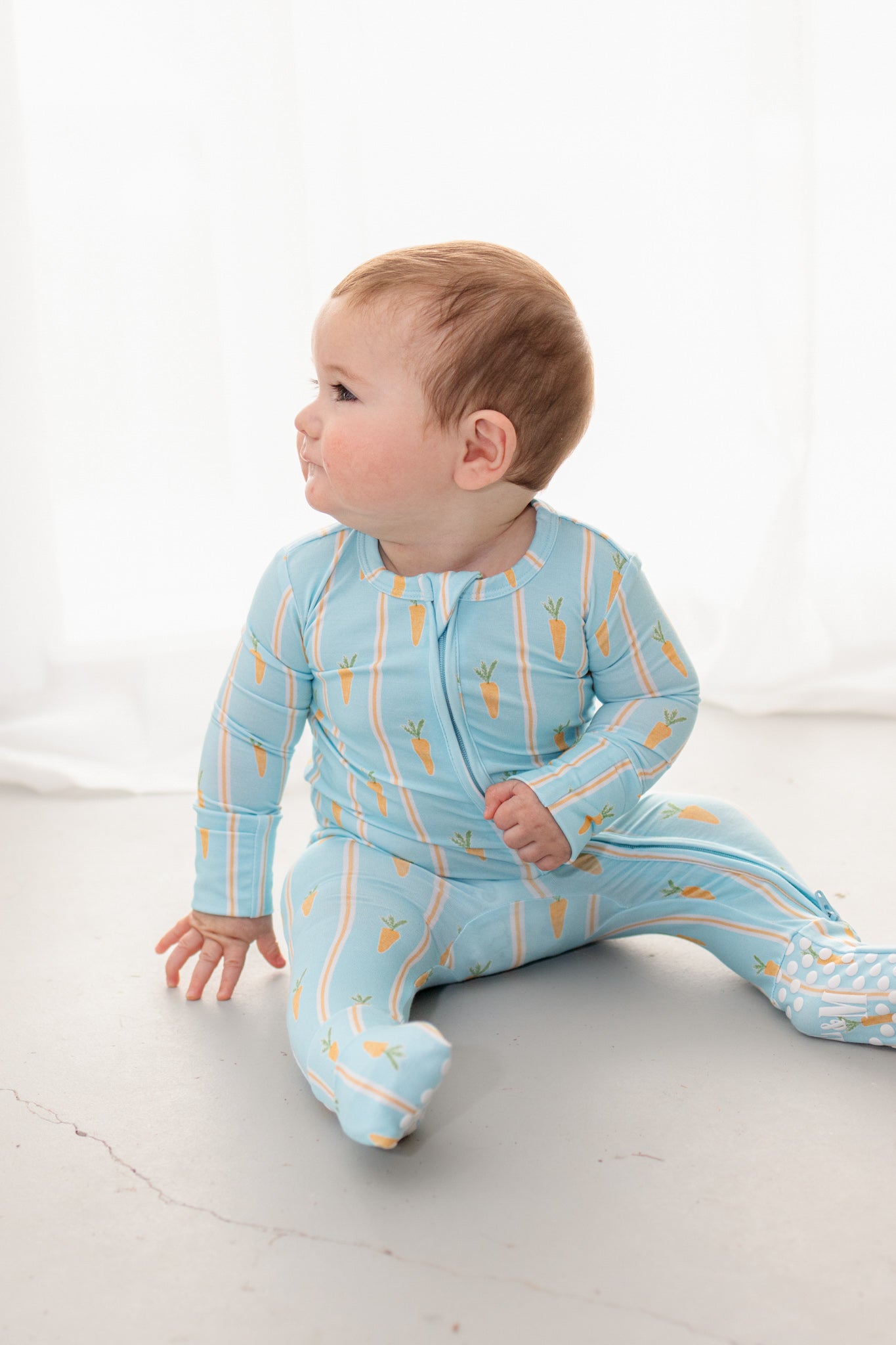 Baby wearing blue Easter bamboo romper  with carrot print. 