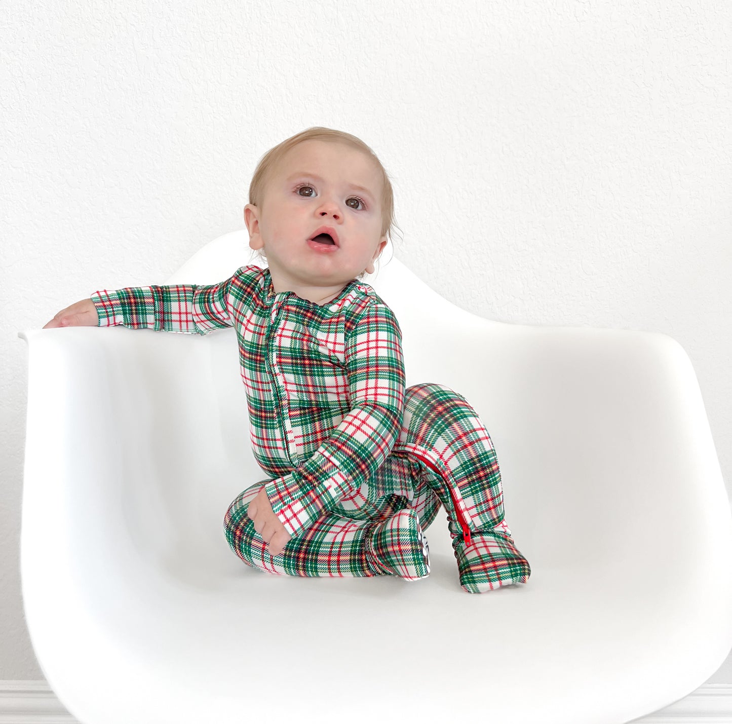 Baby in a cozy classic Christmas plaid print bamboo convertible zip romper, perfect for the holiday season.