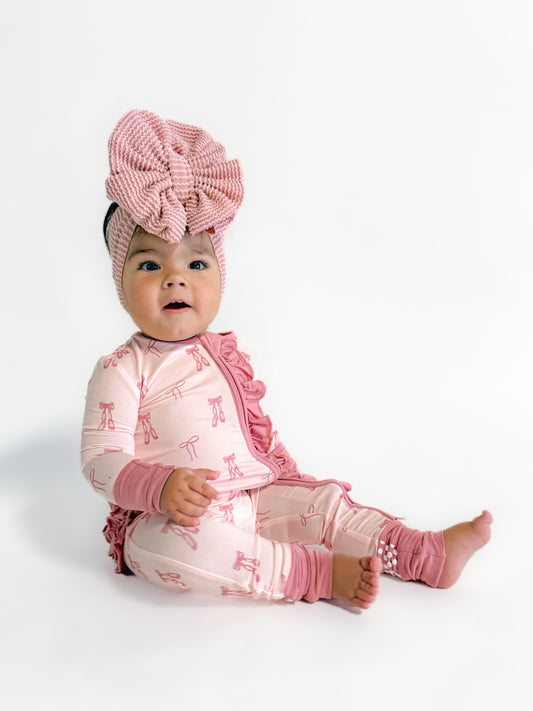 Baby wearing bamboo convertible sleeper with bows and ballet shoes details. 
