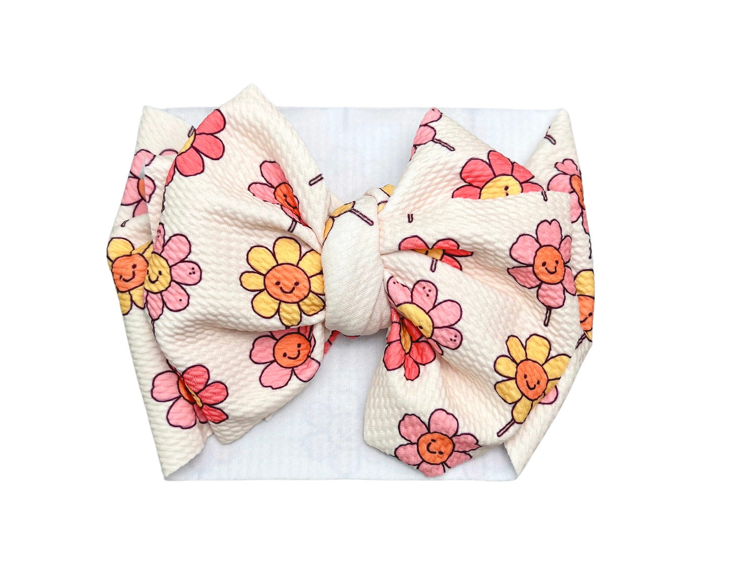 Cute baby headwrap bow with a playful smiling daisy print, perfect for adding a fun touch to any outfit.